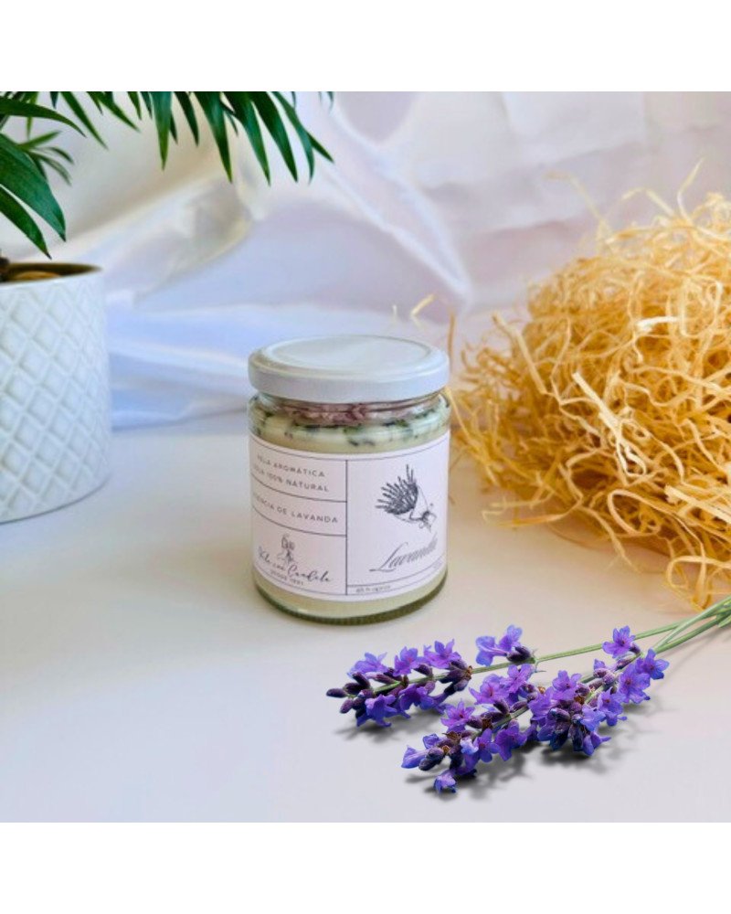 Vela aromática de lavanda con cera blanca y flores secas en recipiente de vidrio